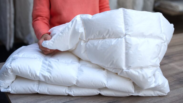 Ein Mann fühlt die Qualität einer Winterdecke mit seinen Händen.