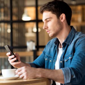 Ein junger Mann bucht einen Beratungstermin auf seinem Smartphone.